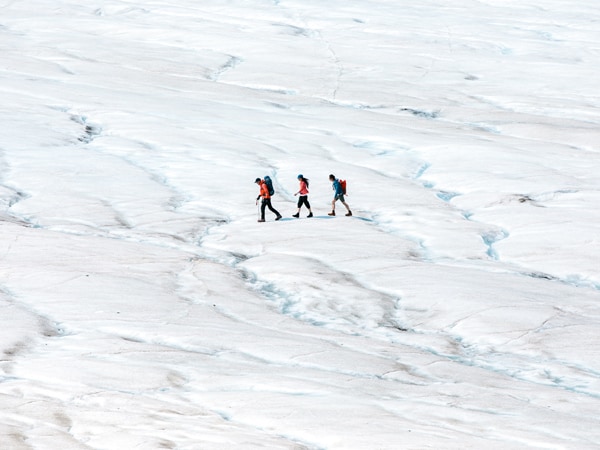 three people walking along Alaska’s Hubbard Glacier