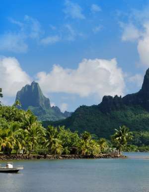 Mountains and ocean with boat in forefront on islands of Tahiti