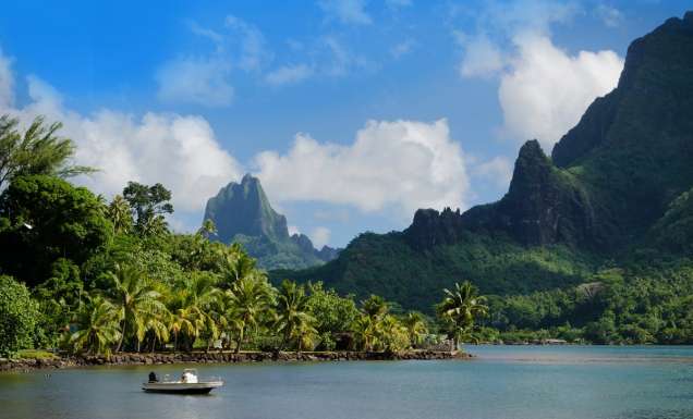 Mountains and ocean with boat in forefront on islands of Tahiti