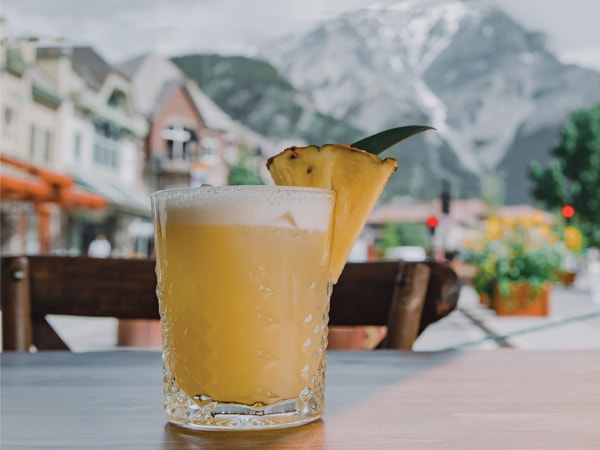a glass of cocktail at Park Distillery with the backdrop of the Rocky Mountains, Banff, Canada