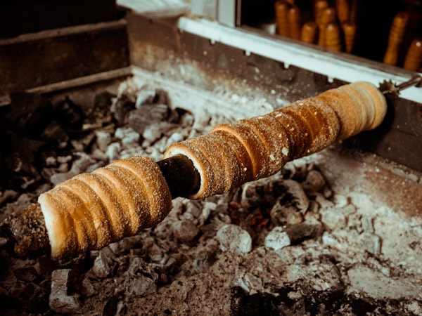 cooking Trdelník on a charcoal grill