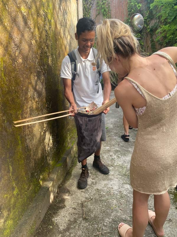 a local guide at Ubud Walking Tour handing long wooden tongs to guests
