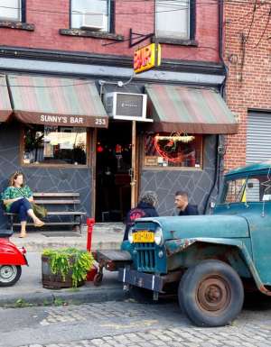 a woman sitting outside Sunny's Bar, Red Hook, NYC