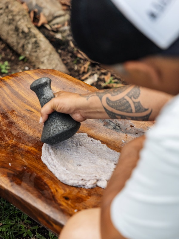mashing cooked starch on a wooden pounding board