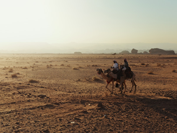 riding a camel along the rugged landscape of Hegra, AlUla, Saudi Arabia