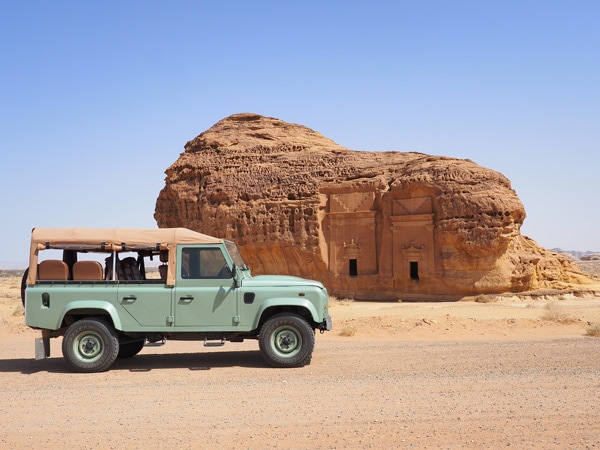 a jeep stopping by the rock-hewn temples of Hegra