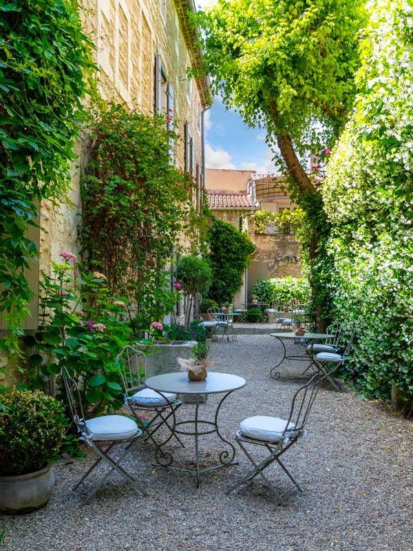 Chairs and tables ready for diners in a small courtyard patio of a restaurant cafe in the historic center of Saint-Rémy-de-Provence, France