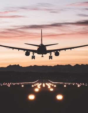 An airplane moments from touching down on the runway at sunrise.