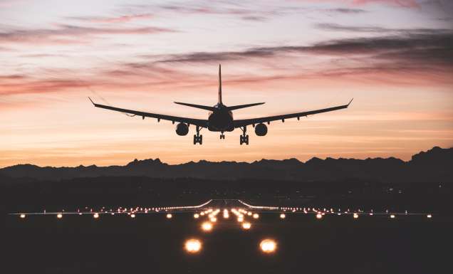 An airplane moments from touching down on the runway at sunrise.
