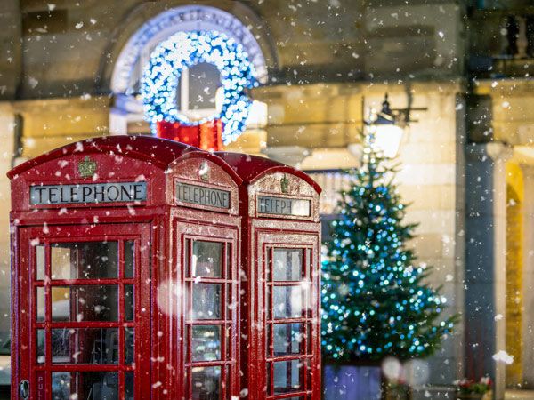 red telephone booths in front of Christmas decorations lights in London, United Kingdom