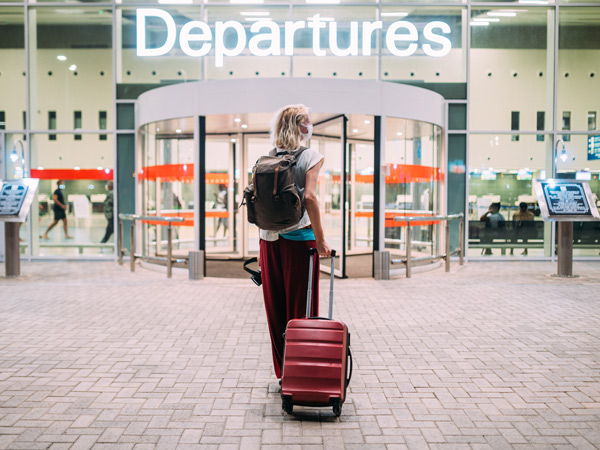 a young woman in front of the departures area at the airport