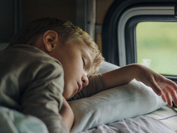 a sleeping boy in front of a train's window