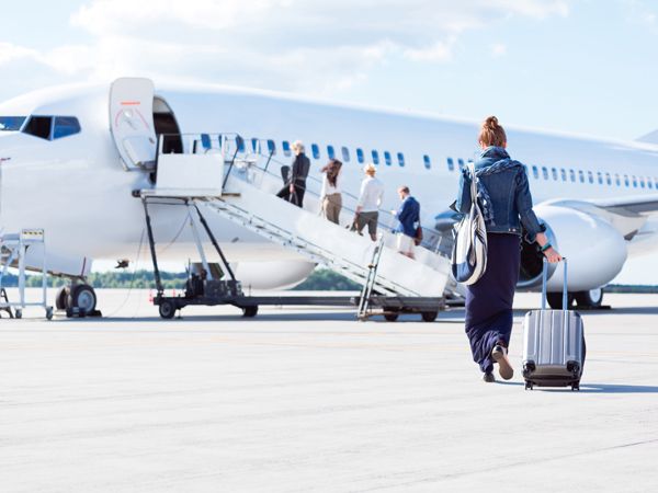 a young woman with luggage walking towards the airplane