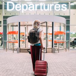 a young woman in front of the departures area at the airport