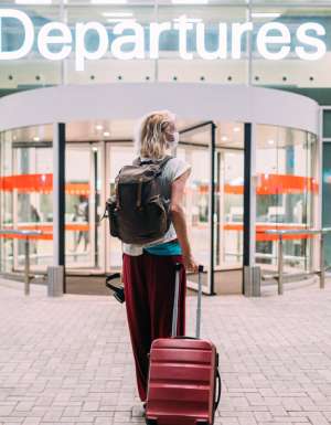 a young woman in front of the departures area at the airport