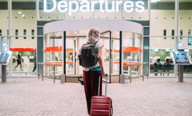 a young woman in front of the departures area at the airport