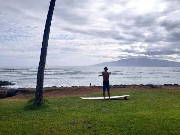 a man standing on a surfboard in Launiupoko Beach Park, Hawai'i