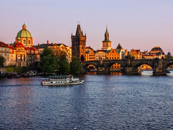a boat sailing along Charles Bridge, Vltava River in Prague, Czech Republic