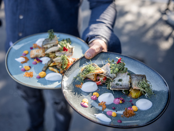 a hand holding food plates at Siriuskogl restaurant
