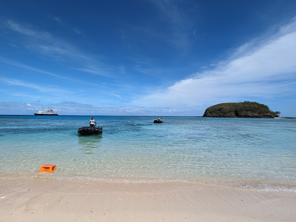 boats arriving on a white-sand beach in Fiji