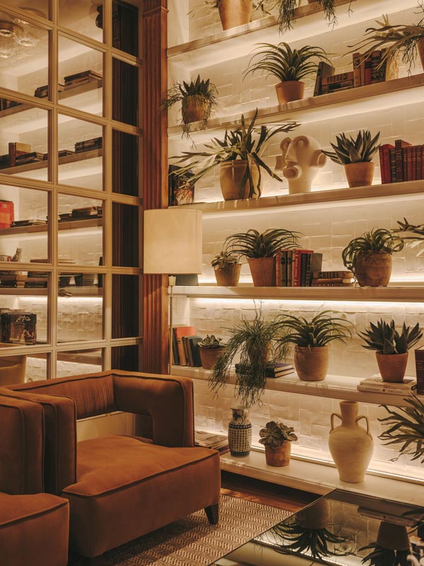 Armchair and bookcase with plants at Hotel Pulitzer in Barcelona