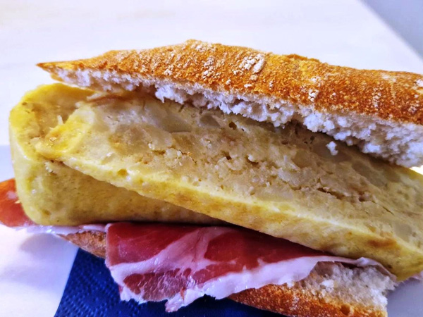 a close-up shot of ham and tortilla bocadillo