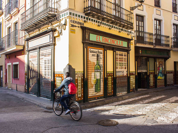 a person riding a bicycle passing by El Rinconcillo, Seville
