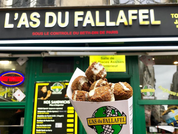 holding a falafel in front of L'As du Fallafel, Paris