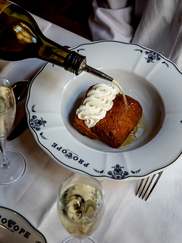pouring liquid over food on a plate at Procope, Paris