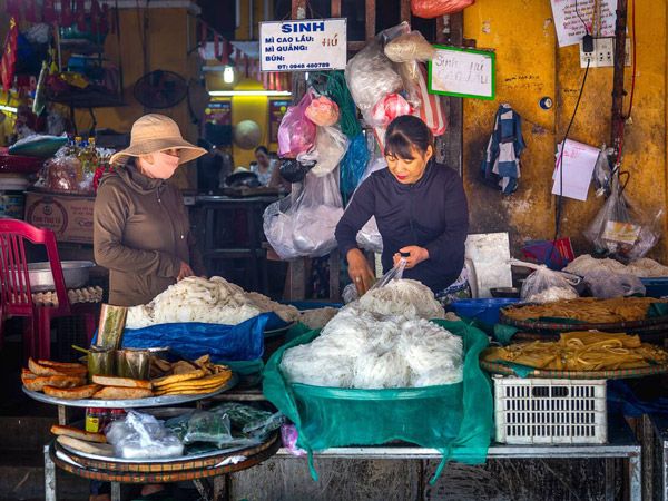 women trimming noodles for cao lau