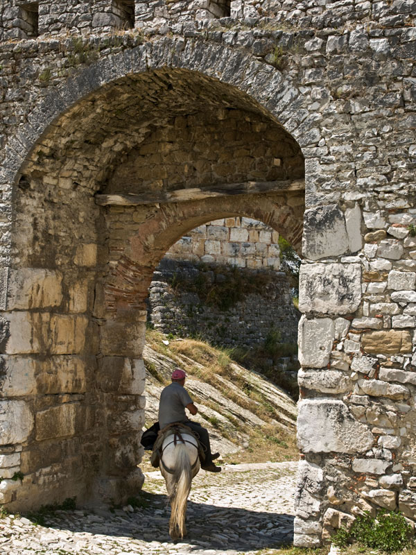 a man riding a horse at the gate to the Citadel of Berat
