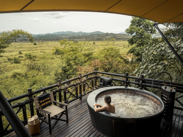 a woman taking a dip in a traditional tub at the Four Seasons TentedCamp