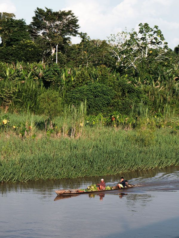 locals paddling a traditional canoe carrying local produce along the Amazon River