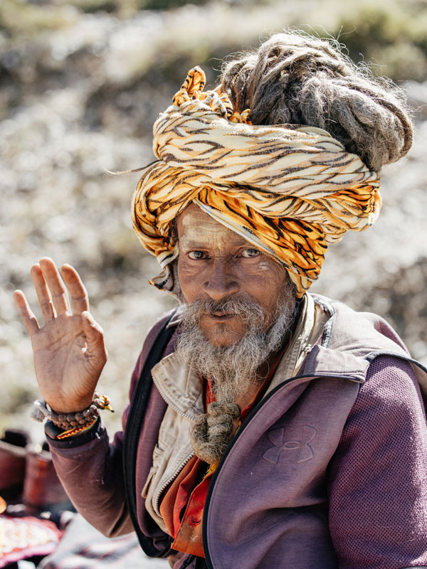 an old Nepalese man waving to the camera