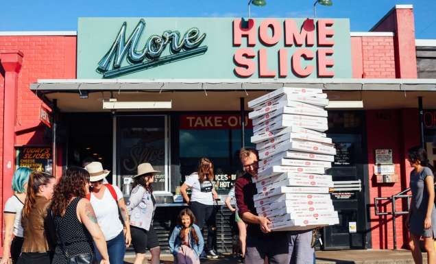 a person holding boxes of pizza outside Home Slice pizzeria, South Congress Avenue