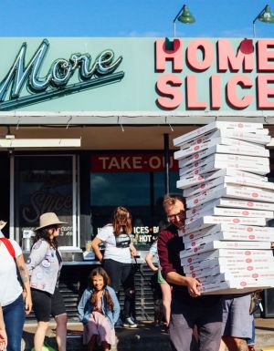 a person holding boxes of pizza outside Home Slice pizzeria, South Congress Avenue