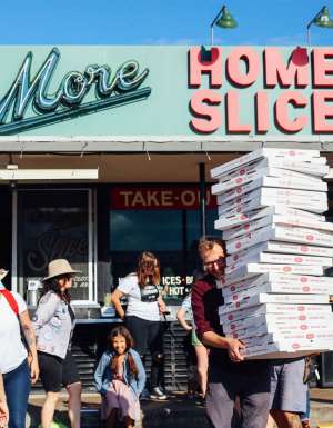 a person holding boxes of pizza outside Home Slice pizzeria, South Congress Avenue