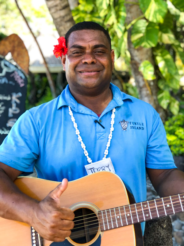 Jerry Tokalau posing for the camera while holding a guitar