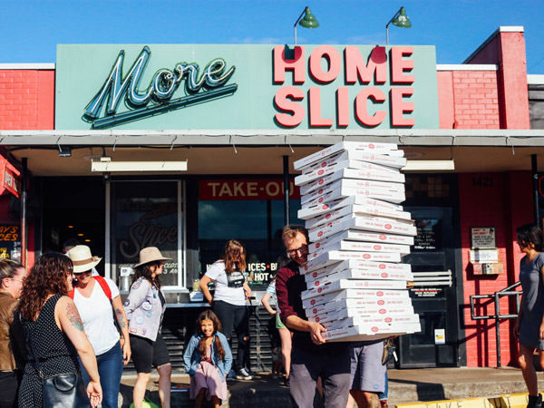 a person holding boxes of pizza outside Home Slice pizzeria, South Congress Avenue