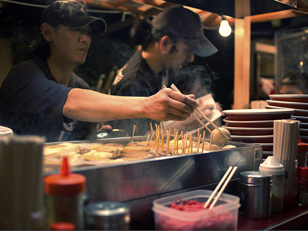 Try out Japan's best regional cuisine in a food stall in Yatai, Fukuoka, Japan preparing fish sticks.