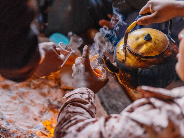 a Bedouin man pouring traditional tea into a cup