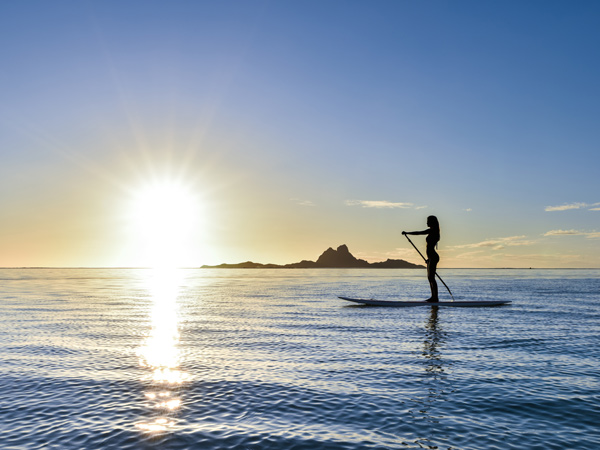 Woman stand up paddleboarding on Taha’a, Tahiti