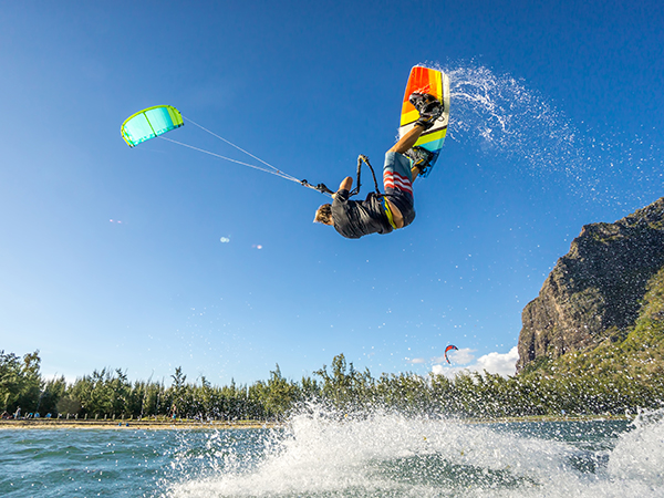 professional kiter makes the difficult trick on a beautiful background of spray and beautiful mountains of Mauritius