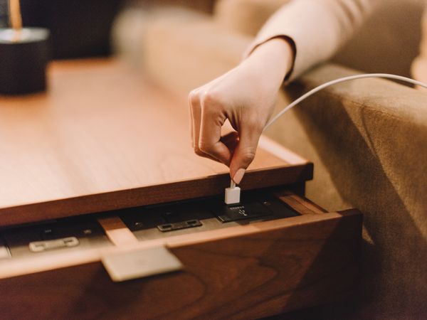a hand plugging in a cable at the charging station in a Cathay Pacific Business lounge