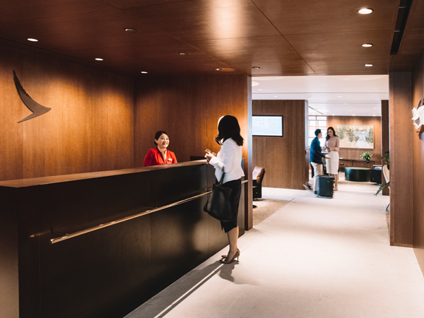 a Cathay Pacific staff welcoming a guest at The Deck, Cathay Pacific Business lounge