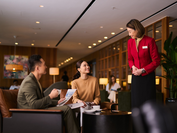 a Cathay Pacific crew staff talking to passengers at The Pier, Cathay Pacific Business lounge
