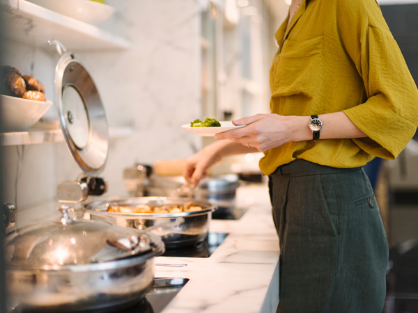 a close-up of a woman getting food at The Wing, Cathay Pacific Business lounge