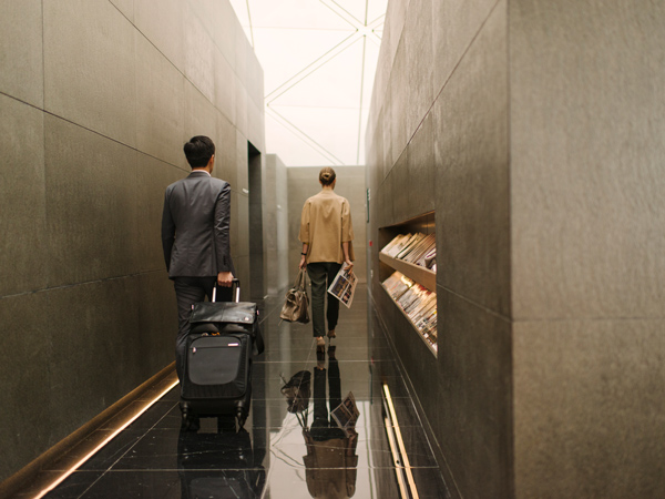 a man carrying a suitcase into The Wing, Cathay Pacific Business lounge