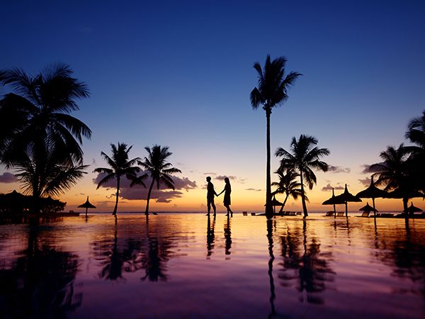 Silhouettes of young couple at scenic sunset on tropical beach in Mauritius