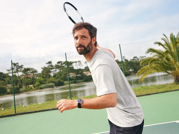 A man playing tennis wearing the ScanWatch 2 in black.